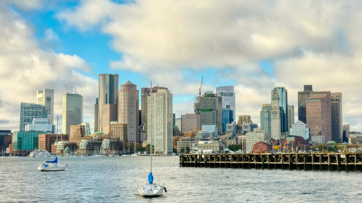 Skyline of skyscrapers by the water under a partly cloudy sky.