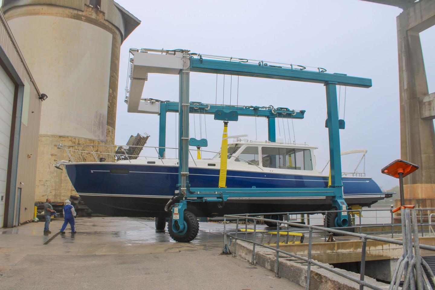Blue boat on a lifting frame at a shipyard.