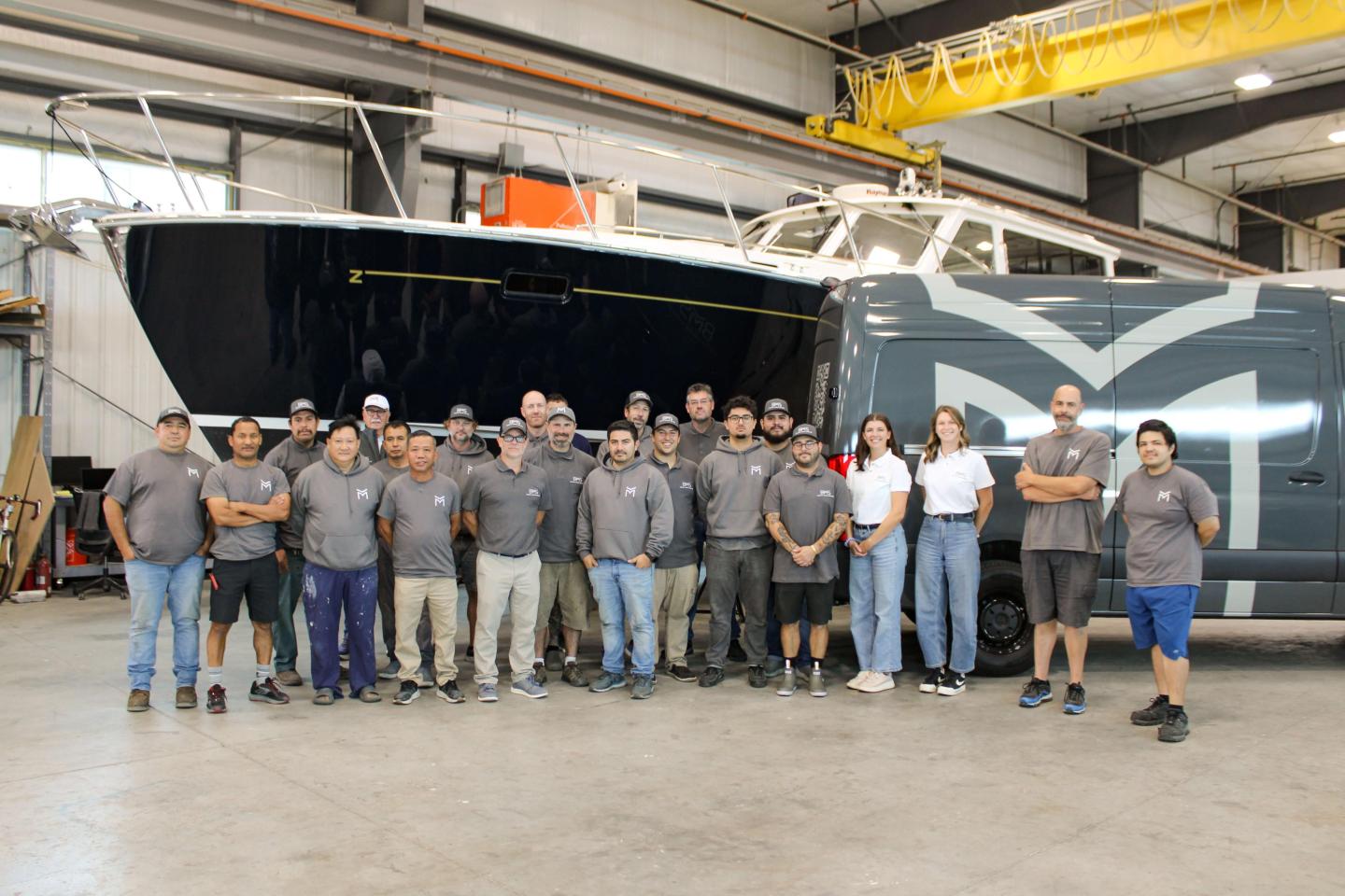 BMS staff standing in front of a boat and van, smiling.