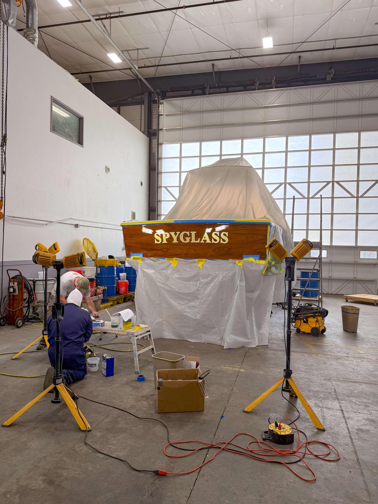 Workshop with tools, covered boat, and person working.