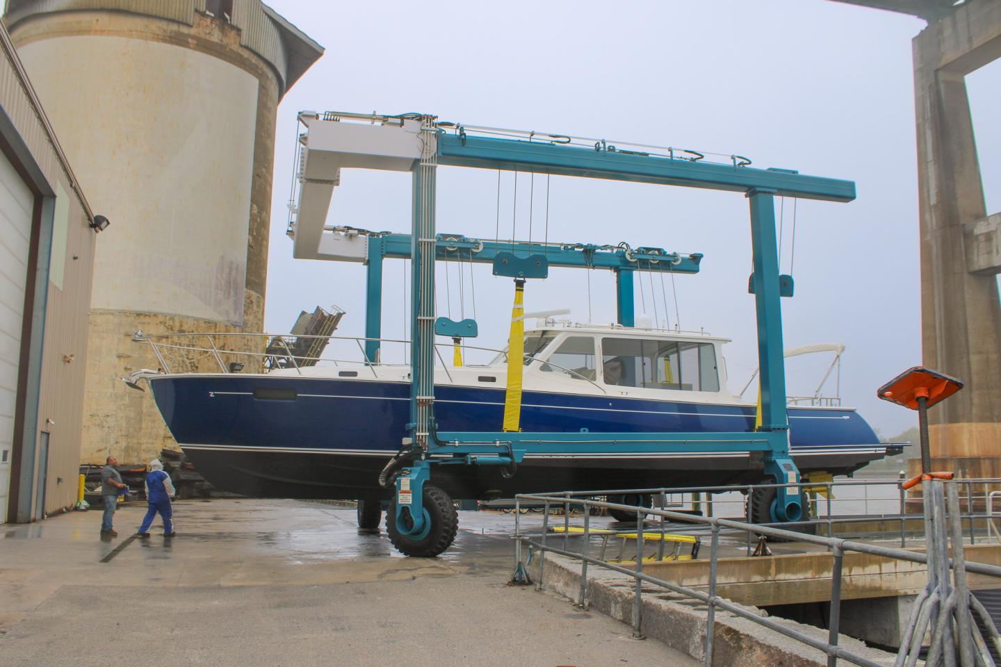 Blue boat on a wheeled lift in a shipyard.