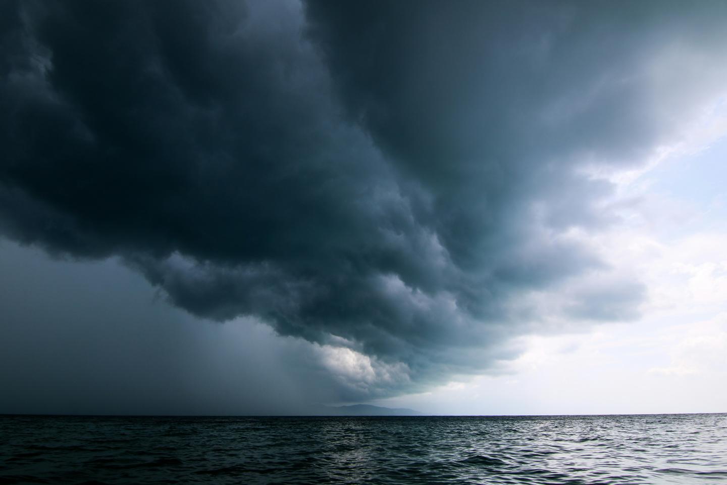 Dramatic dark storm clouds over a calm sea.